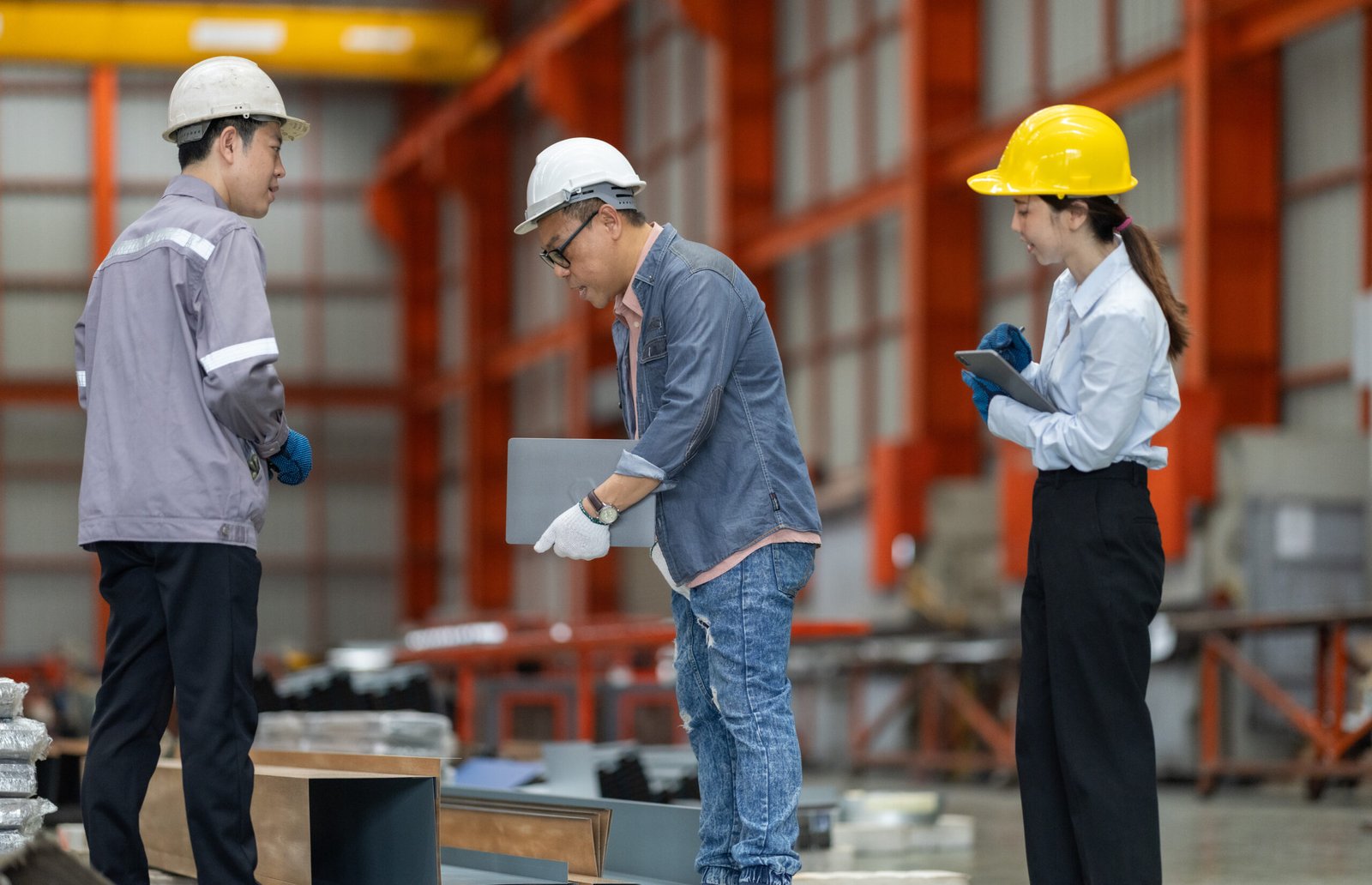 Engineer and technician, including a female professional, engage in precise measurement and data analysis on the factory floor to ensure the highest quality in metal fabrication processes.